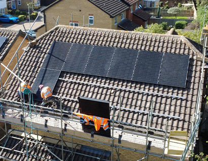 Two electricians installing solar panels on a roof with scaffolding in Aylesbury.